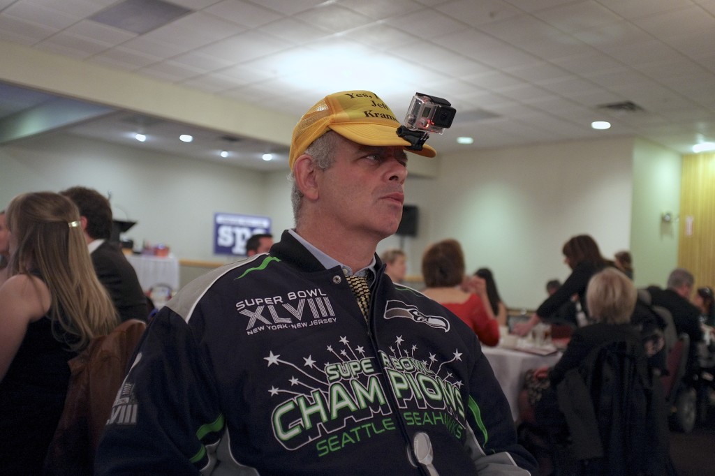 Jeff Kramer, wearing his Seahawks jacket and a video camera on the bill of his hat, mingles at the Syracuse Press Club awards banquet at Drumlins. Michael Davis Photo | Syracuse New Times