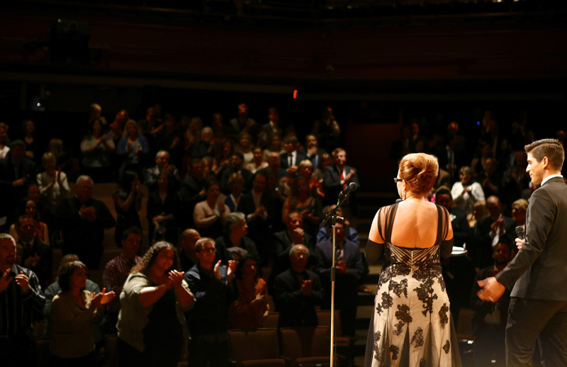 Two people stand on a stage in formal attire looking out to a full crowd at a previous SALT Awards Ceremony. The SALT Academy sees 24 shows a year and votes for the best in more than 25 categories.