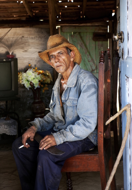 Miquel’s skin glistens from sweat as he sits down to enjoy a cigarette. He has just returned home from working in the fields where he has been cutting grass with a machete and wooden gancho which he uses as an aid in pull the grass that has been cut out of his way