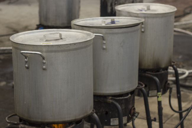 A close up shot of three tall, metal pots used for boiling crawfish.