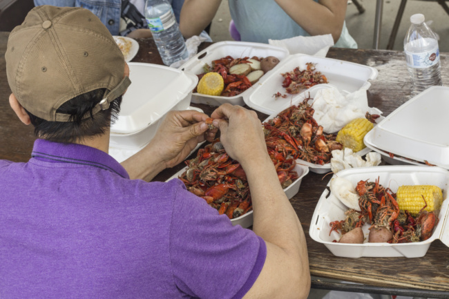A group shot of a picnic table, where at least three containers of crawfish are spread out in a smorgasbord. 
