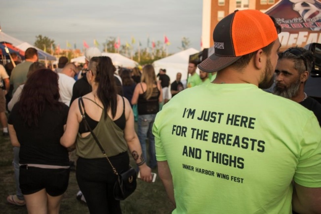 A man's joke T-shirt reads "I'm just here for the breasts and thighs" with the Wing Fest 2018 logo underneath.