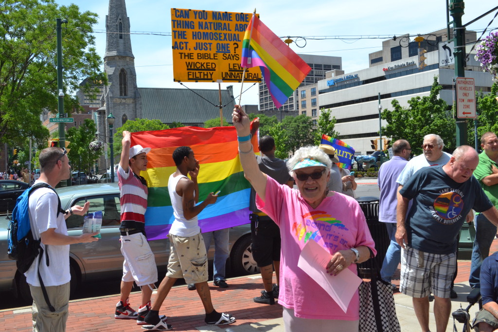 Attendees block the lone protestor who showed up for the rainbow flag raising over city hall. (Photo by Ty Marshal) 