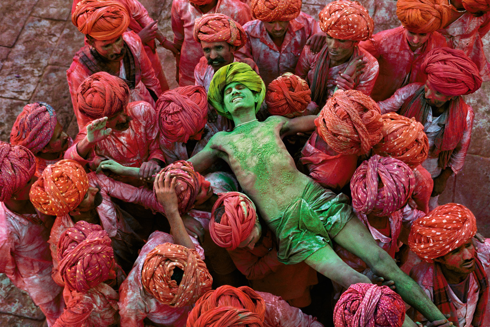 00211_17, Rajasthan, India, 1996, INDIA-10005NF4. Holi Man. MAX PRINT SIZE: 60X80 Man gets carried by a group of men at Holi festival.The Holi festival is also known as the festival of colors and this image by McCurry shows why. With powder bombs exploding around him, this man is in a state of reverie as he is carried aloft through the crowd. In form and content it is an image of intense fervor and excitement. Magnum Photos_NYC94205, MCS1996002K308 final print_MACRO final print_Genoa final print_Sao Paulo final print_Milan '09 Phaidon, Iconic Images, final book_iconic India_Book Stern Portfolio_Book Fine Art Print retouched_Sonny Fabbri 02/10/2015