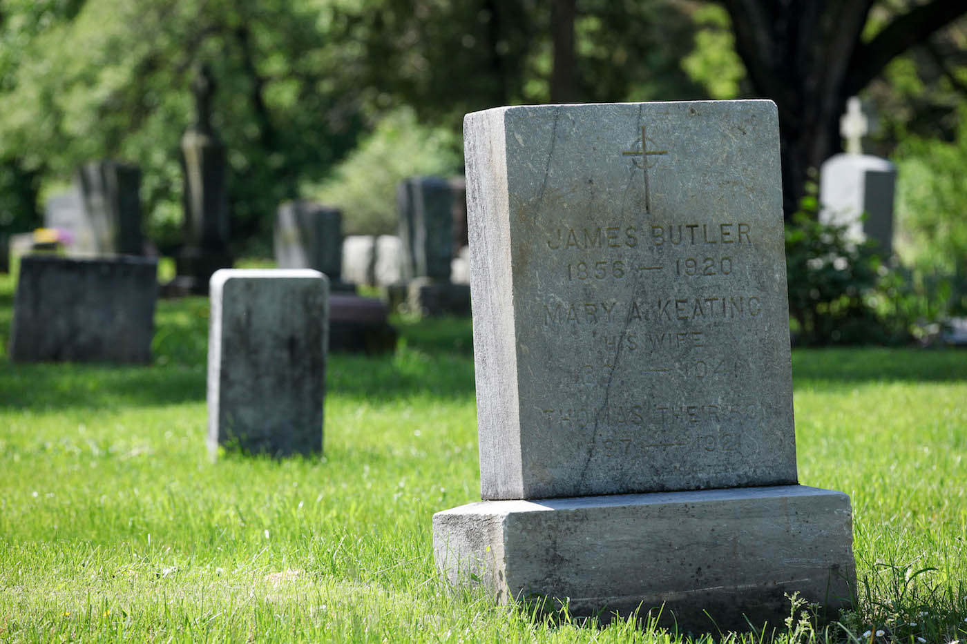 An old, worn rectangular headstone with Thomas F. Butler's name on it. Above are the names of his parents, who he was buried near.