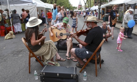 A shot of a trio playing musical instruments in the street during the Arts Week arts and crafts fair.