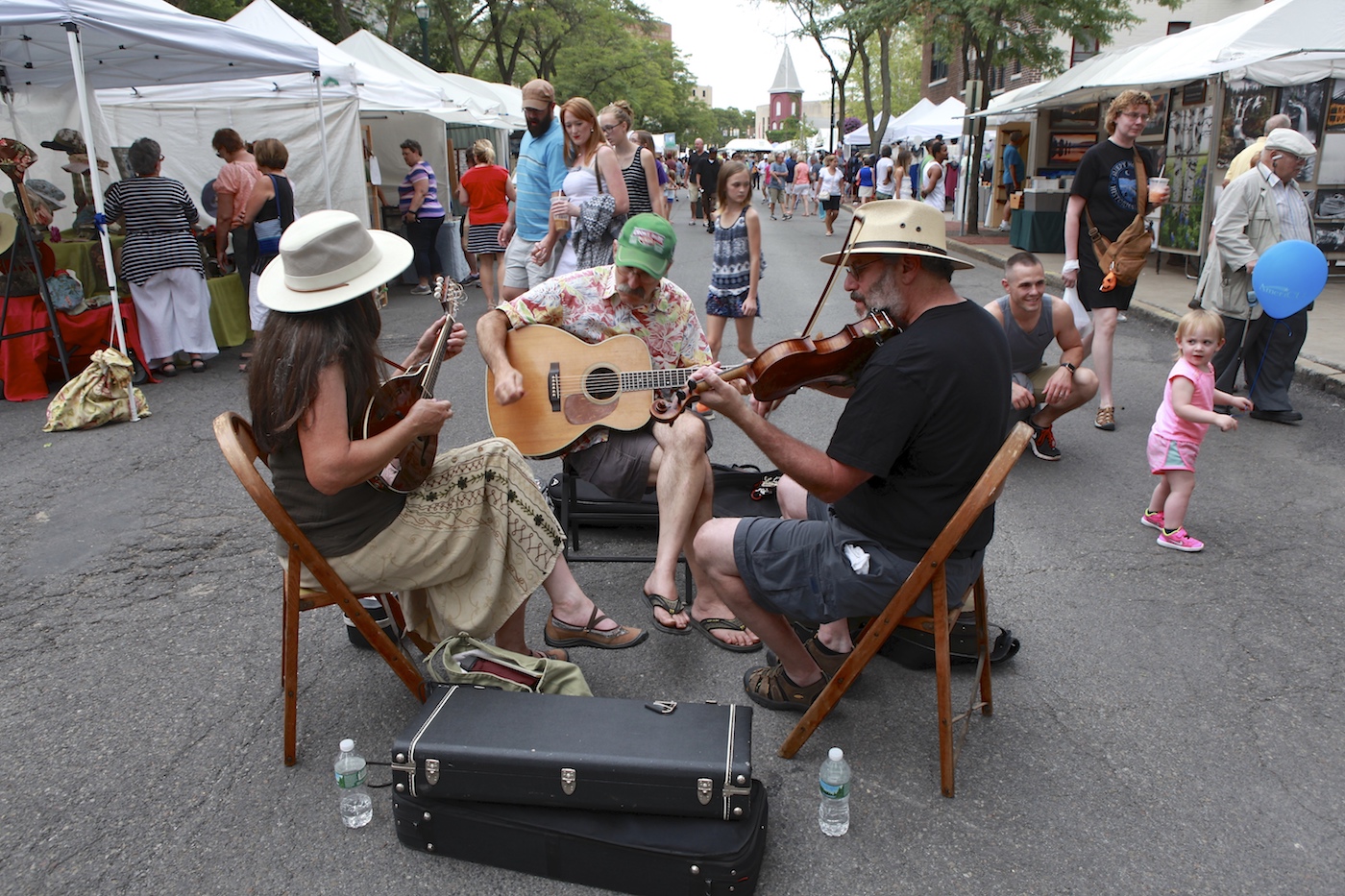 A shot of a trio playing musical instruments in the street during the Arts Week arts and crafts fair.