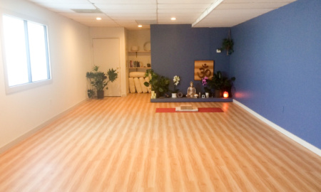 A picture of the studio space at Mindful Yoga. The space is small and long, with a frosted window along one side for privacy.