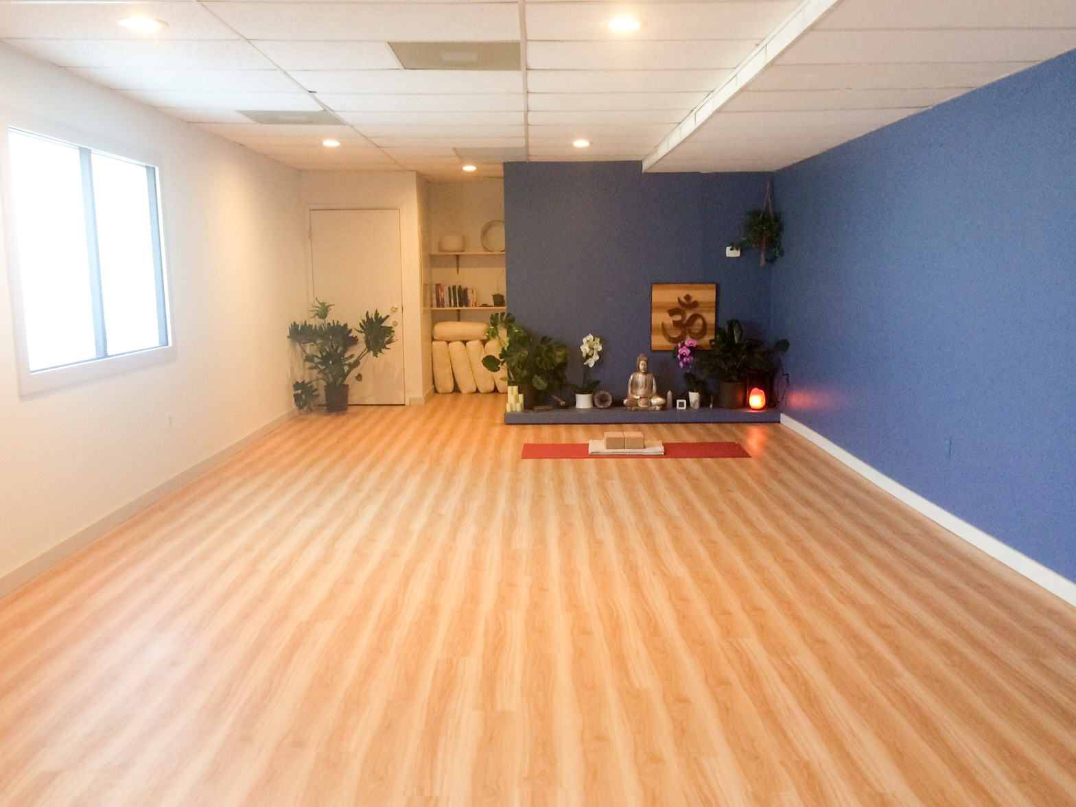 A picture of the studio space at Mindful Yoga. The space is small and long, with a frosted window along one side for privacy.