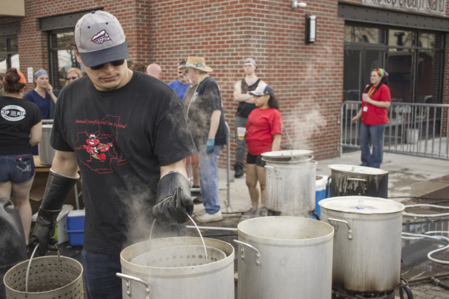 A server carries tall pots of boiling water as he prepares to cook up more crawfish for the hungry crowd.