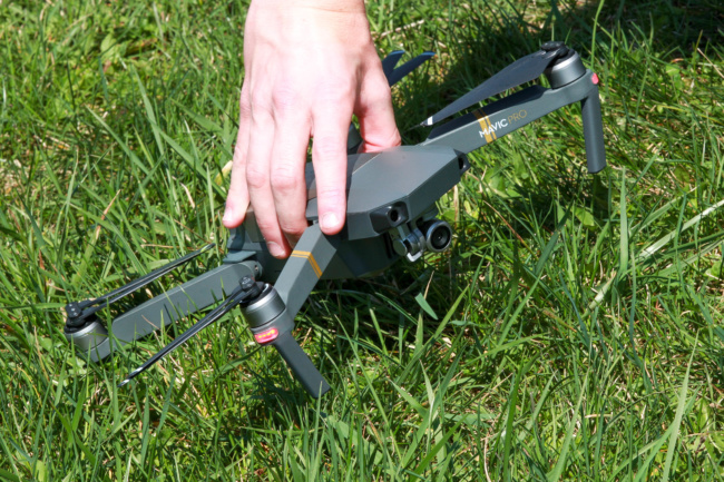 A close-up shot of the drone while it sits on the ground in the grass. Chase Guttman tilts it forward so you can get a look at the small camera on the front.