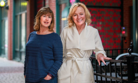 Two women, the creators of the Cut to the Chase dating app, stand facing the camera.