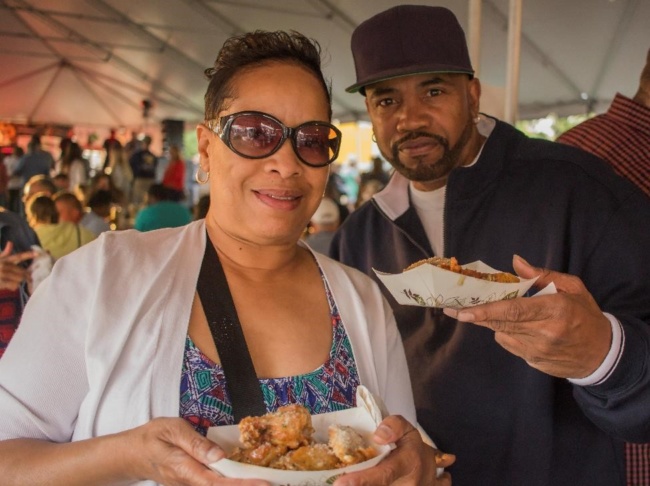 A man and a woman hold up their plates to pose for a photo at Wing Fest 2018
