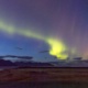 A deep purple sky with yellow Northern Lights over a grassy plane.