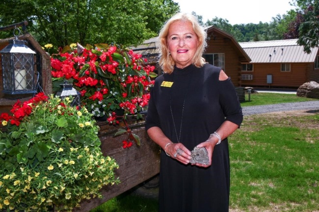 Dr. Renee Scialdo Shevat, owner and president of the Herkimer Diamond Mines, poses for a photo near some blooming flowers.