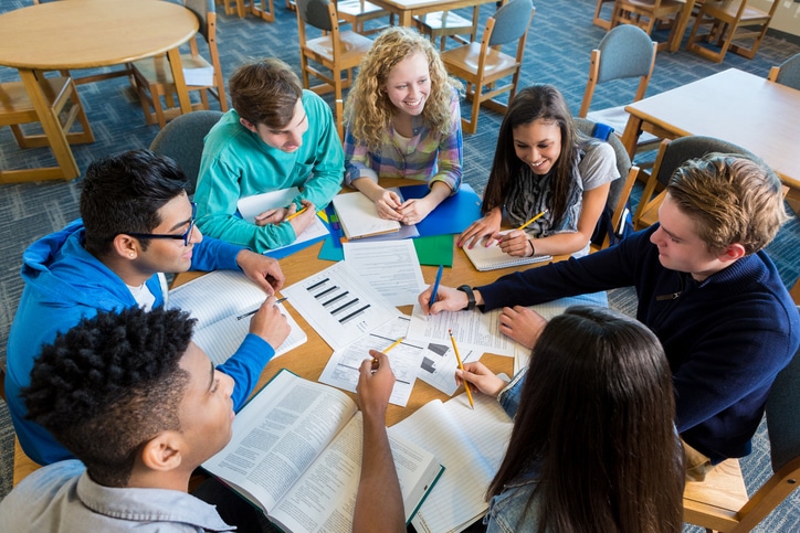 A group of teenagers sit around a table doing homework. Teens are still too young to vote in elections.