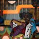 Artowrk by Jaleel Campbell has a digital, angular feel with bright colors. It depicts an African-American couple lounging together.