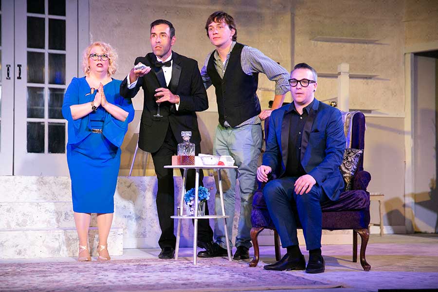 Four cast members from It's Only a Play do a scene, monologuing around a small table.