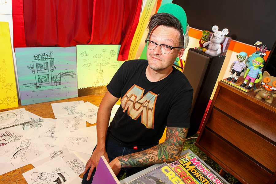Artist Tommy Lincoln sits on the floor of his studio surrounded by sketches.
